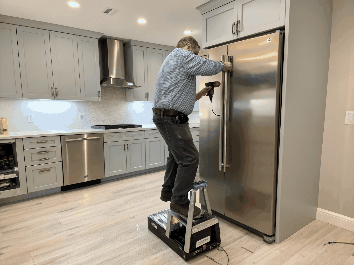 Licensed technician repairing a Kenmore refrigerator in a Kennesaw kitchen